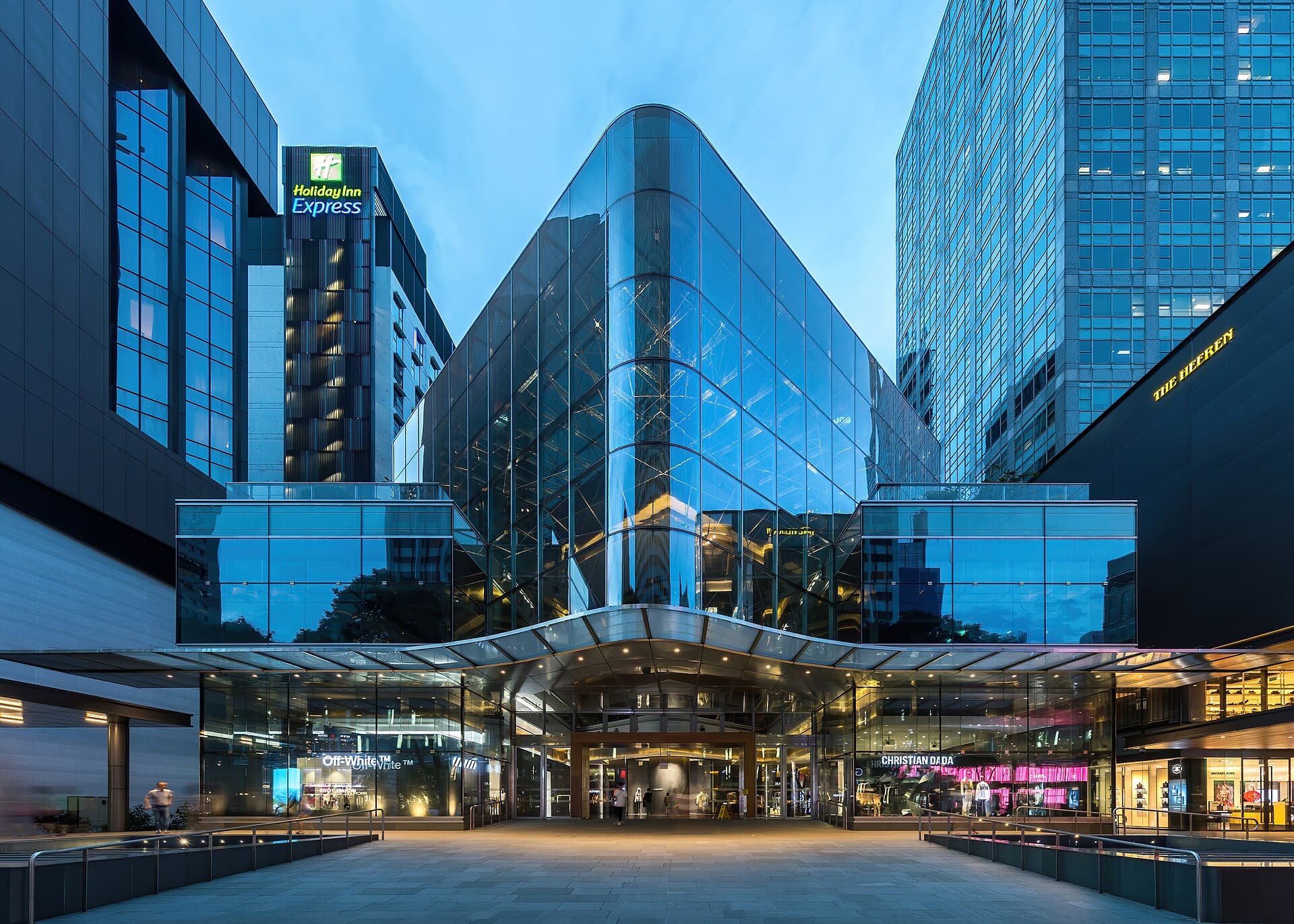 Illuminated glass façade along Orchard Road at blue hour